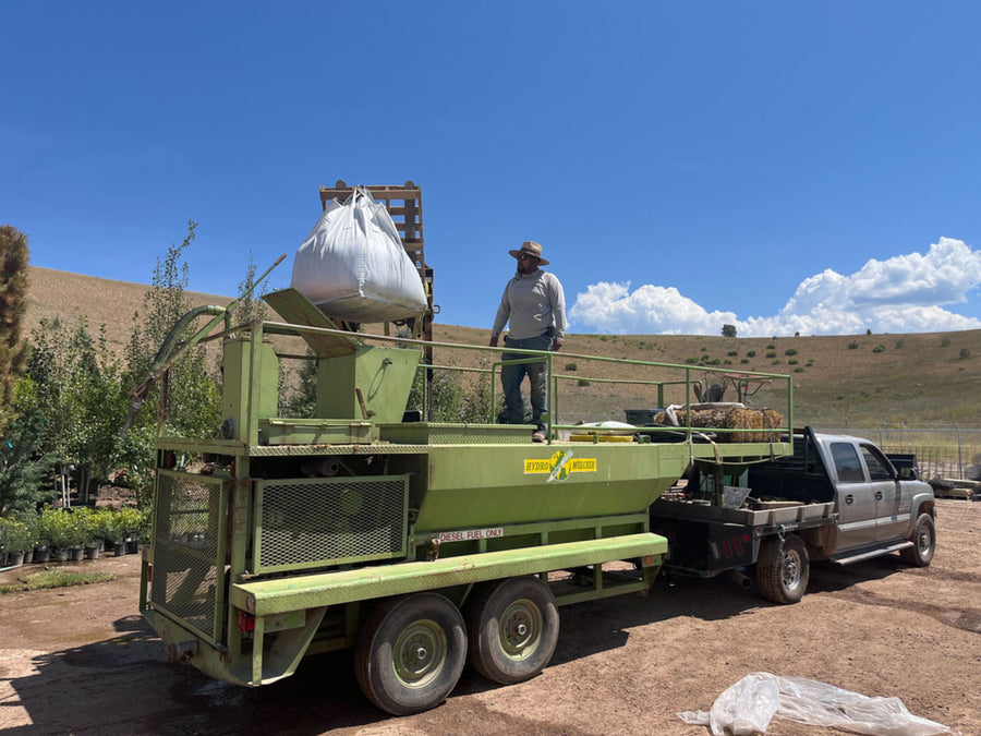 Crew loading a CarbonizPN super sack onto a spreader trailer